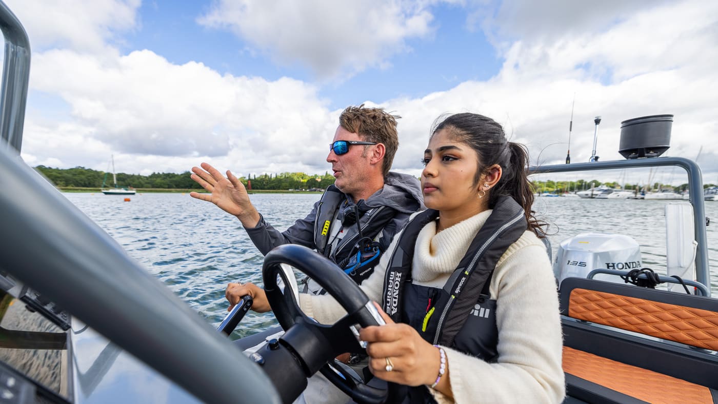 Instructor coaching a student at the wheel of a powerboat RIB on the River Hamble
