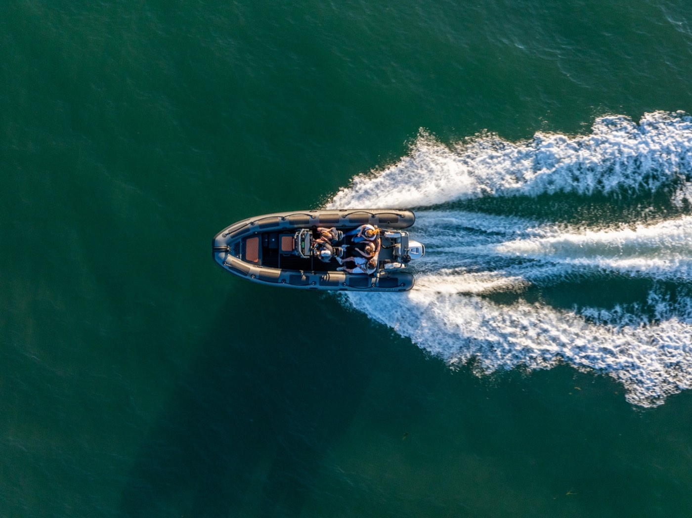 Aerial view of a training RIB planing across the Solent leaving a white wake